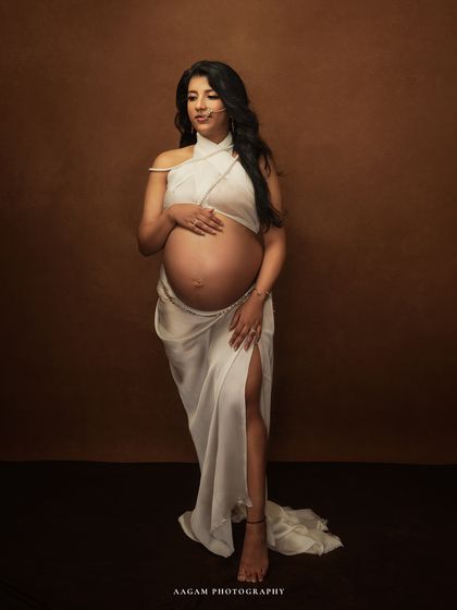 A full-length portrait of the mother-to-be in a Grecian-style drape. The pose is one of strength and grace, a modern goddess of motherhood.