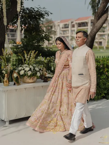 The bride and her father walking down the aisle, a poignant and beautiful tradition. The path is lined with white flowers, creating a pure and sacred walkway.