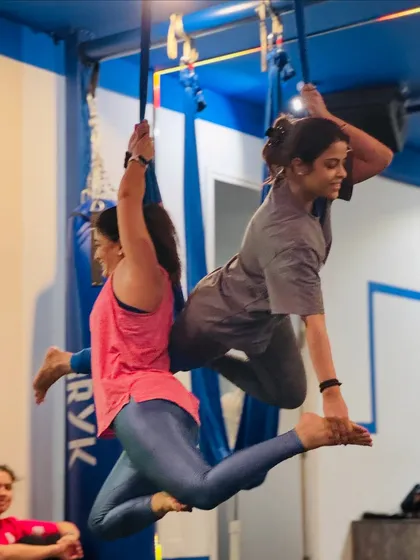 Partner aerial yoga builds trust and communication. Here, two members work together to create a beautiful, synchronized pose.
