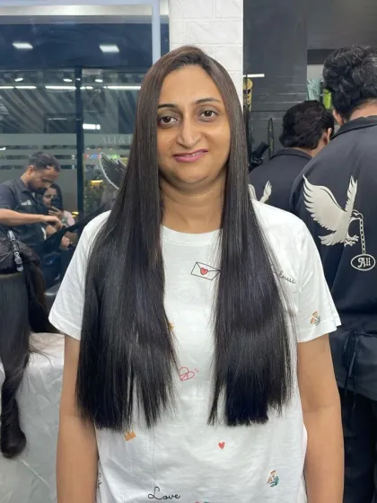 A happy client showing off her very long, straight, and healthy hair after a styling session.