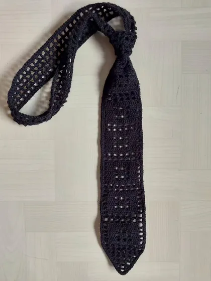 A flat-lay of the filet crochet tie, showing the full length and construction.