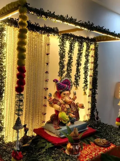 A throwback to a classic design, this mandap features a canopy of dark green leaves and hanging floral strings. The warm lighting and traditional marigold garlands create a cozy and devotional atmosphere.