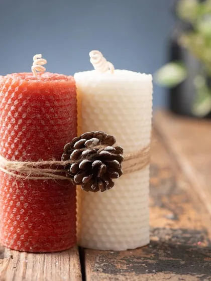 These textured beeswax pillar candles in red and white are tied together with twine and a pinecone, giving them a lovely rustic feel.