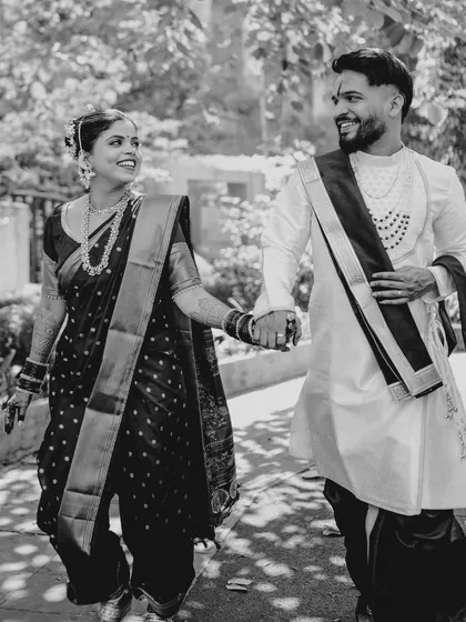 A happy, candid moment of the couple walking, captured in classic black and white. This style emphasizes their joyful expressions and the movement in the scene.