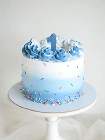 Simple, sweet, and perfect for a first birthday photoshoot. This blue ombre smash cake with colorful sprinkles is designed to be as fun for your little one to dig into as it is beautiful.