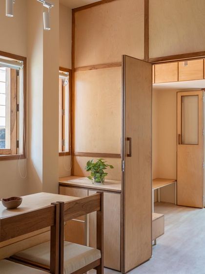 The waiting and consultation area is filled with natural light, with simple wooden furniture and a connection to the green space outside.