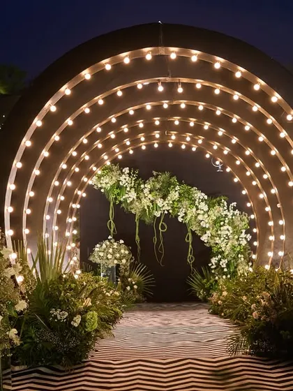 Your Sangeet entrance should be nothing short of dramatic. I designed this illuminated tunnel with a bold chevron-patterned floor and lush white florals to build excitement and welcome guests into a night of celebration.