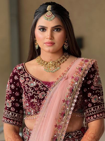 A direct portrait of the bride, showcasing the beautiful embroidery of her outfit and the clean, precise makeup application.