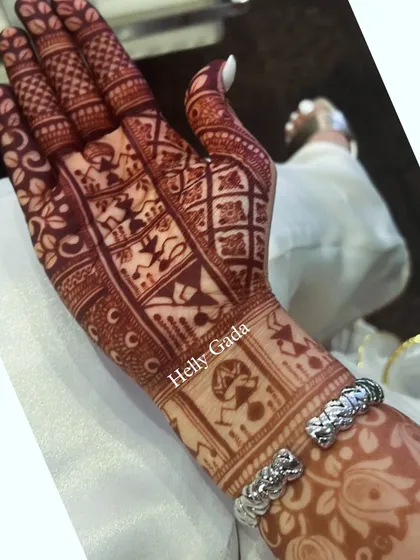 The rich, dark stain of the Warli art design. The geometric shapes and simple figures of the Warli paintings look even more striking with the deep henna color.