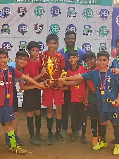 Champions in the making. Our young football stars celebrate a tournament victory, holding their trophy and medals high. This is the result of their hard work and teamwork.