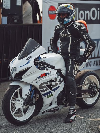 A rider on a custom Suzuki GSX-R drag bike, complete with an extended swingarm, waits patiently for his run. This is a machine built for one thing: straight-line speed.