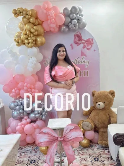 A lovely 'Bow-tiful' birthday setup featuring a pink bow and teddy bear theme. The birthday girl poses in front of the personalized backdrop and pink, white, gold, and silver balloon arch.