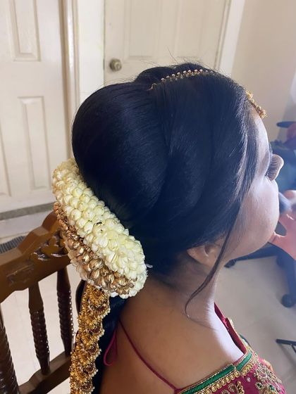 Another angle of the traditional bridal bun and braid, showing how the accessories are secured. This detailed view highlights the craftsmanship involved in creating a perfect Muhurtham hairstyle.