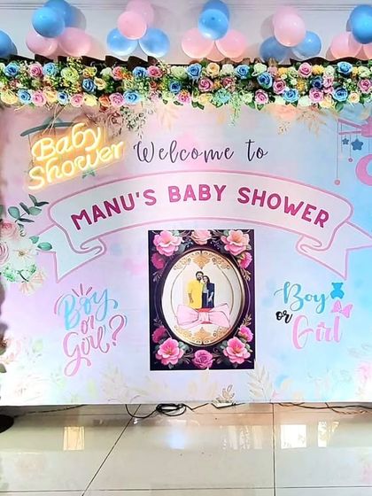 A beautiful 'Boy or Girl?' gender reveal baby shower backdrop, featuring a floral frame, a custom print, and a neon sign.