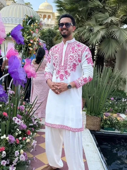 Another shot of the client in the white and pink embroidered kurta at a beautiful outdoor event.