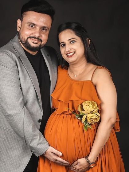 A happy studio portrait of an expecting couple. She is wearing our vibrant mustard gown, which adds a pop of color and joy to the photograph.