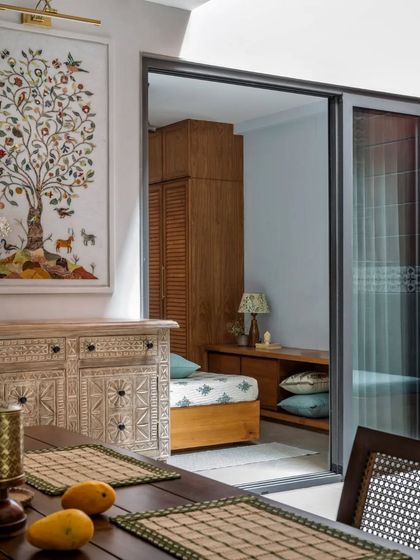 A sliding door opens from the dining room to a bedroom, showcasing how the home uses traditional art, like the 'Tree of Life' tapestry, to tell a story.