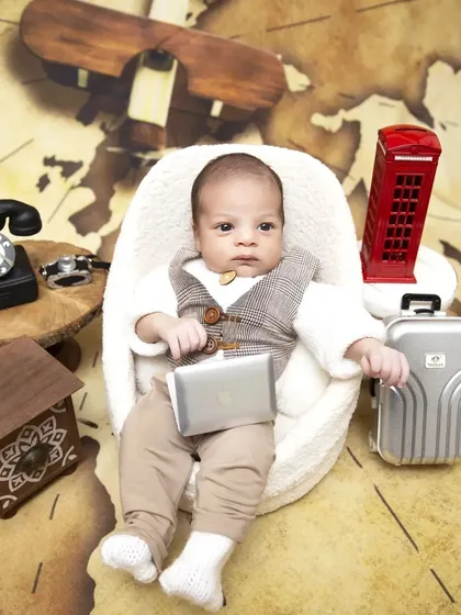 Not all babies sleep through their session, and I love capturing their bright, curious expressions. This "Boss Baby" travel theme features an awake newborn with fun props like a miniature laptop, suitcase, and a vintage telephone.