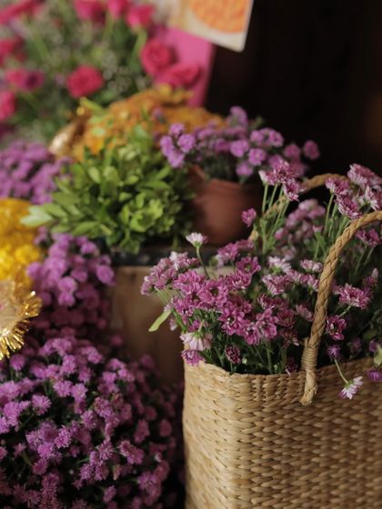 A close-up of purple flowers in a rustic wicker basket, showcasing the textures and colors of our bohemian-inspired Haldi decor.