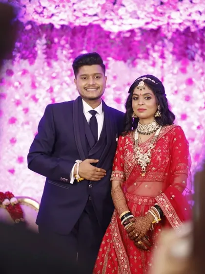 A modern reception look for a beautiful couple. The bride's red lehenga is paired with glamorous makeup and a chic hairstyle, perfect for the evening celebration.