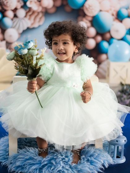 A candid shot of a toddler holding a flower, with a beautiful smile. Her personality shines through in this photo.