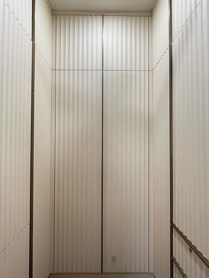 A direct view into the walk-in closet, showcasing the beautiful texture created by the vertical fluted panels. The off-white color keeps the space feeling bright and airy.