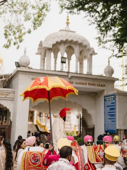 The groom's grand entrance, the Baraat, arriving at the Gurudwara. This shot captures the color, energy, and tradition of the procession before the Anand Karaj ceremony.