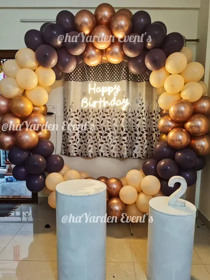 A simple and sophisticated balloon ring in muted, earthy tones. The 'Happy Birthday' neon sign adds a modern touch to this cozy home setup.
