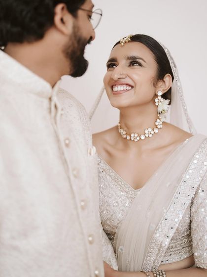A radiant smile from the bride, Lorraine, as she looks at her groom, Vassim. Their all-white attire for their ceremony is a picture of elegance and grace.