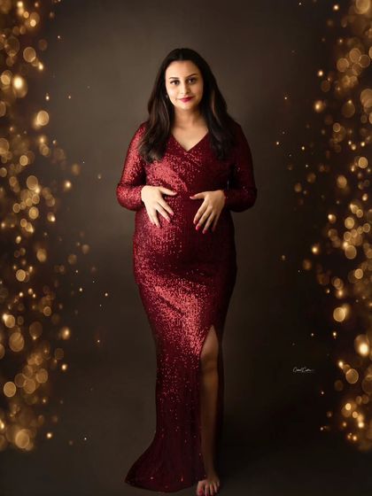 Surrounded by a magical bokeh of golden lights, this mom-to-be shines in a festive red sequin dress, perfectly capturing a celebratory mood.
