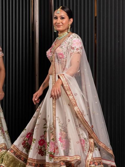A model gracefully walks in the floral pre-loved lehenga, showing its beautiful movement and fit. It's a sustainable and budget-friendly way to get a stunning wedding outfit.