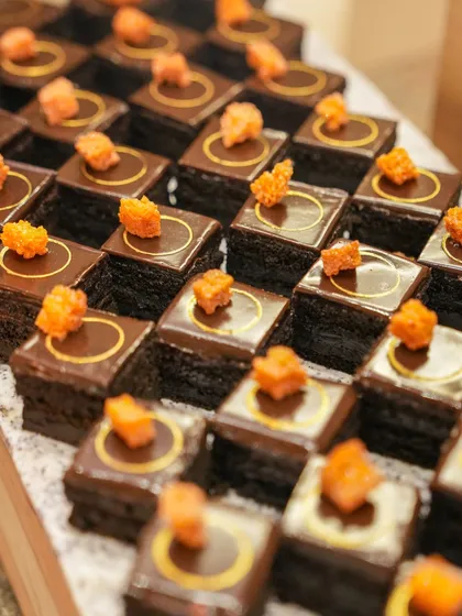 Elegant chocolate pastries with a glossy finish and a delicate orange garnish, showcasing our refined pastry work.