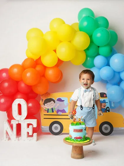 The birthday boy, with a little cake on his face, smiles happily. Cake smash sessions are all about celebrating with joy and a little bit of mess.