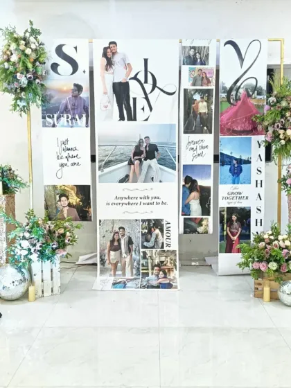 A beautiful way to tell your love story. This personalized photo backdrop features custom banners with the couple's pictures and names, framed by elegant floral arrangements on sequin stands.