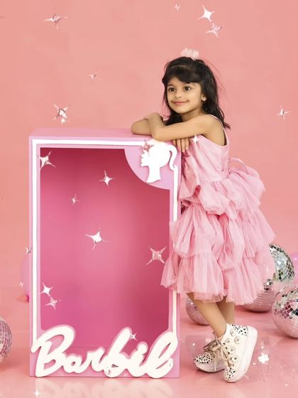 Leaning against her life-sized Barbie box, this little girl strikes a pose. It's a stylish and fun shot from her fifth birthday celebration.