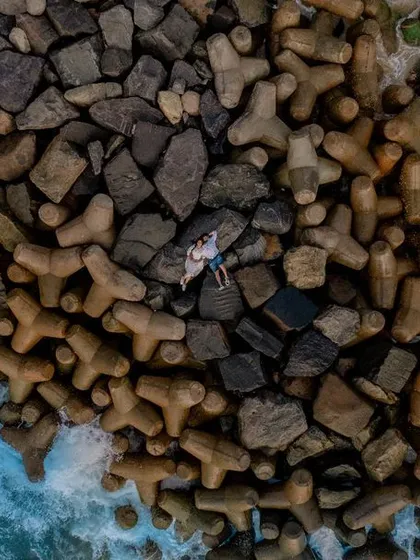A stunning aerial drone photograph of a couple on the coastal breakwaters of Karnataka. Our pre-wedding shoots often feature the dramatic and beautiful landscapes of our home.
