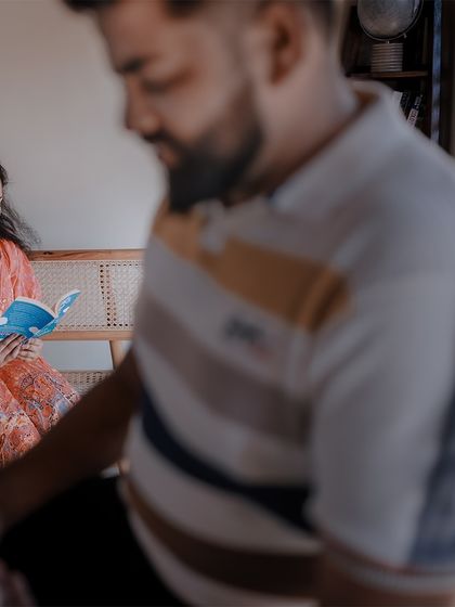 An intimate indoor moment, with the bride-to-be reading a book while her partner looks on.