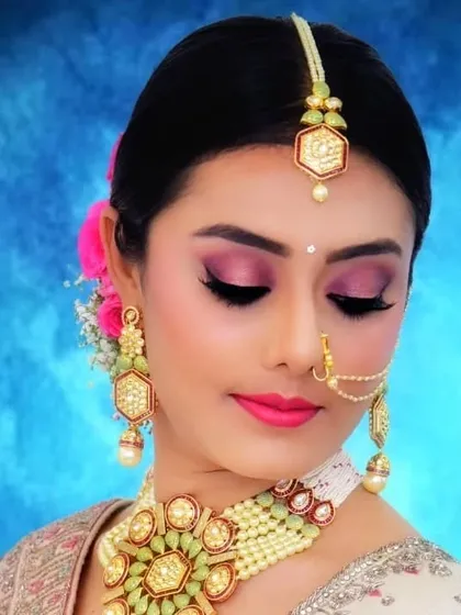 A beautiful shot of the client's bridal makeup. Her hair is styled in a neat bun with a pink rose, which complements the pink tones in her makeup.