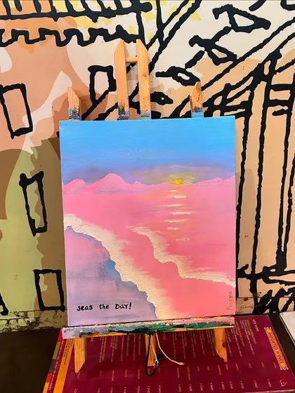 "Seas the Day!" A finished pink-hued beach painting resting on an easel, ready to be admired.
