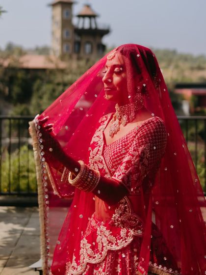 A close-up shot of the bride through her veil. The focus is on her radiant skin and the way the light catches the details of her makeup.