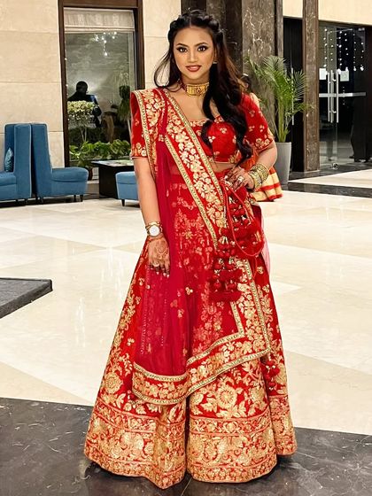 A perfect example of smiling with her eyes. This full-length shot in a classic red lehenga shows a complete bridal look that is both traditional and glamorous.