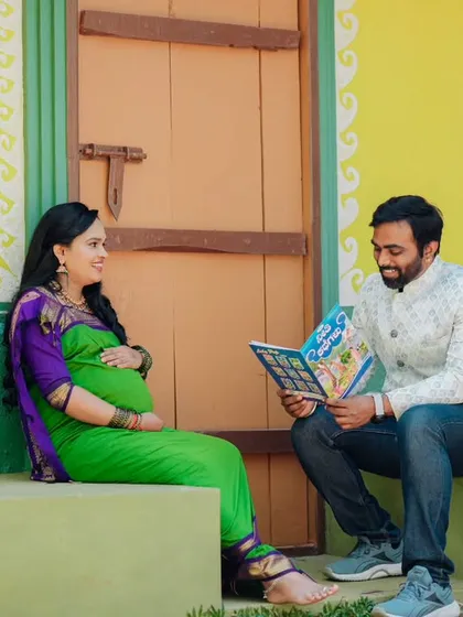 A creative shot showing the father-to-be reading a children's book to the baby bump in a colorful, rustic setting.
