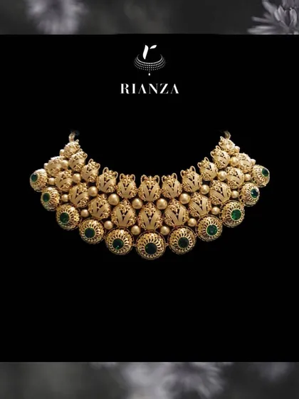 A grand gold necklace featuring intricate nakshi work and studded with green stones. This type of design is inspired by South Indian temple jewellery and is perfect for a traditional ceremony.
