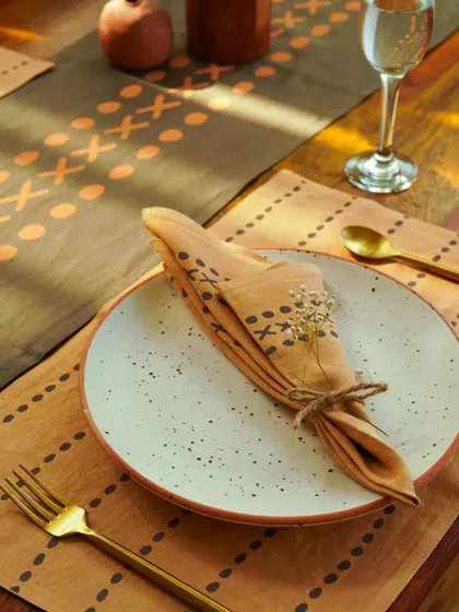 A close-up of a beautifully folded napkin on a ceramic plate, part of a table setting that exudes rustic charm.