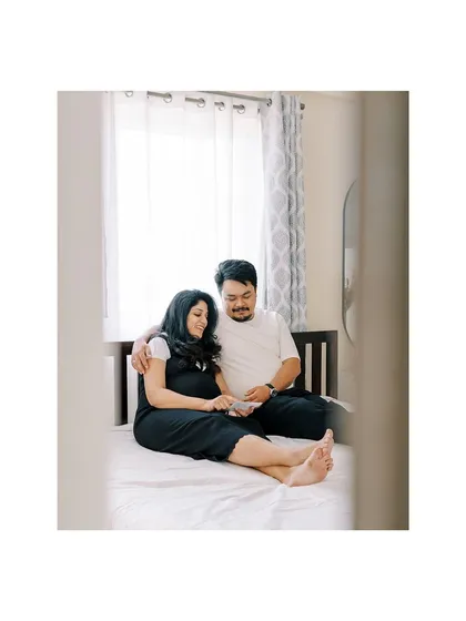 A wider shot of a couple on their bed, looking at the ultrasound scan. This image captures not just the moment, but also the comfortable, personal setting of their bedroom.