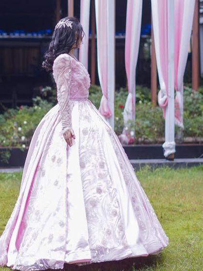 A side profile of the pink ball gown, showing the detailed embroidery on the sleeves and the graceful way the fabric falls. It is a truly timeless and romantic piece.