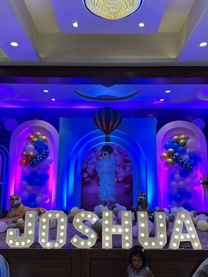 A unique theme for Joshua's birthday, combining hot air balloons with jungle animals. This wide shot shows the full stage with marquee letters, a personalized photo backdrop, and various props.