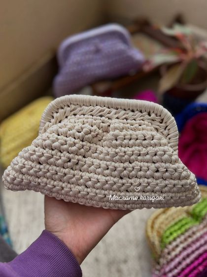 This off-white macramé clutch is a versatile and elegant accessory. The intricate knotting provides a beautiful texture, making it a sophisticated choice for any event.