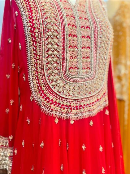 A detailed shot of the heavy embroidery on a bright red kurta, perfect for a bride or wedding guest.