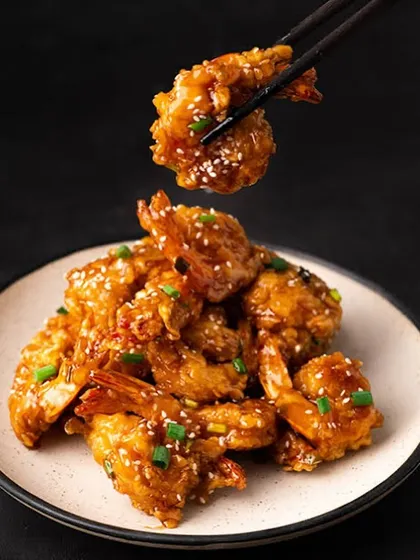 Golden bites of crispy honey garlic prawns. These are perfectly crunchy, tossed in a sweet and savory sauce, and sprinkled with sesame seeds.